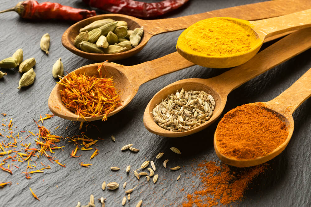 Wooden spoons of cardamom, turmeric, saffron and spices on slate